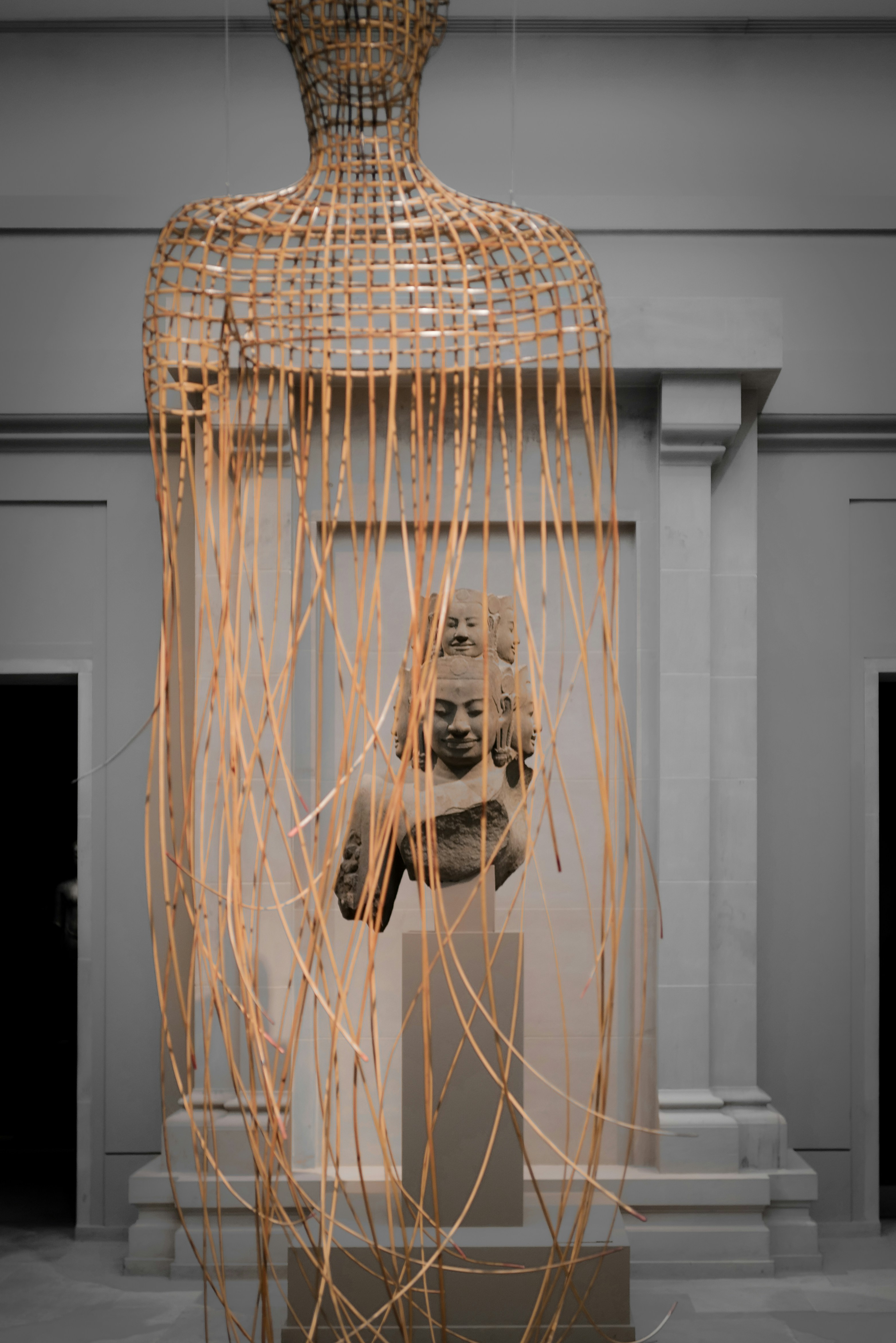 Skulptur einer Büste in einem geflochtenen Käfig.