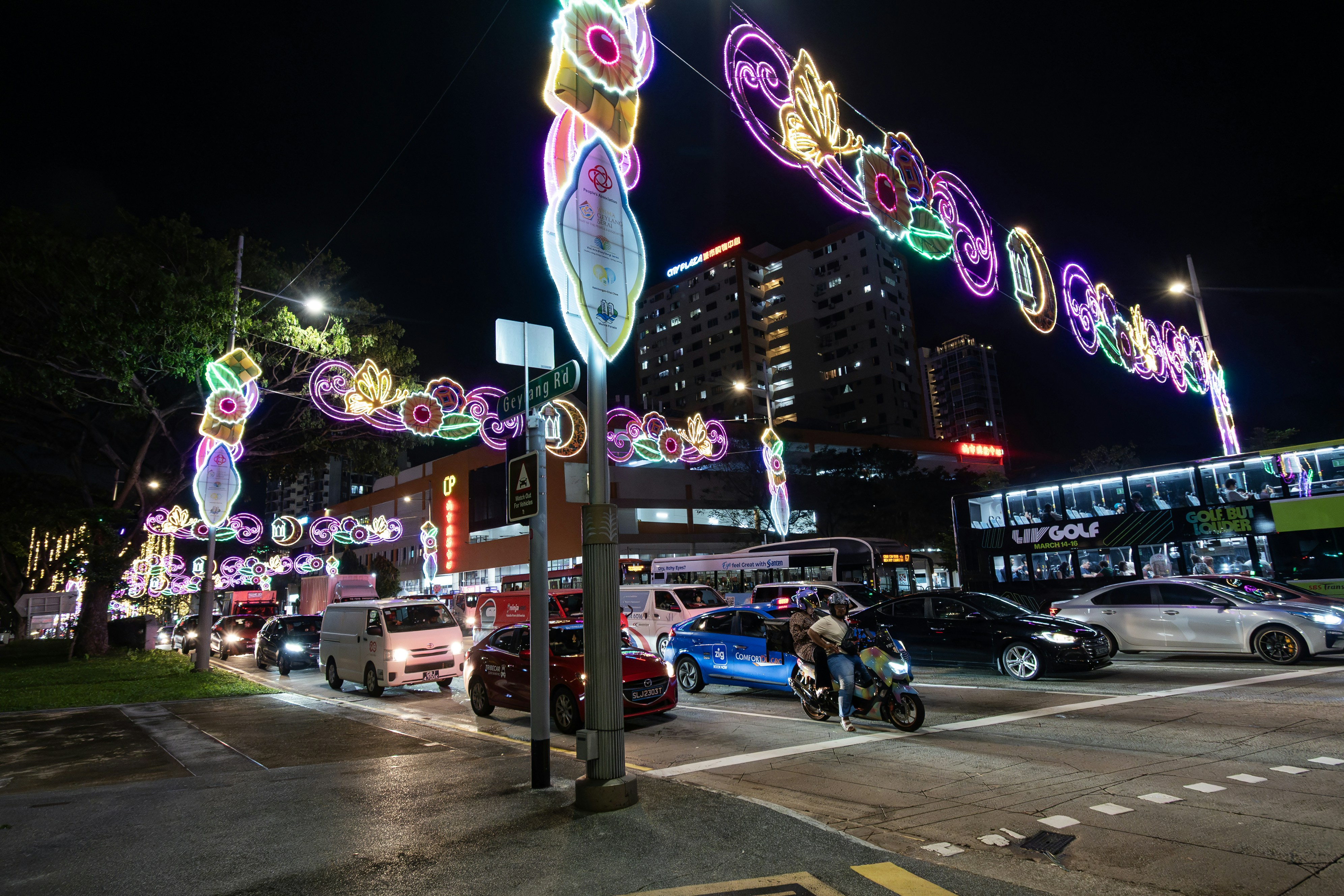 Colorful lights illuminate a busy city street at night.