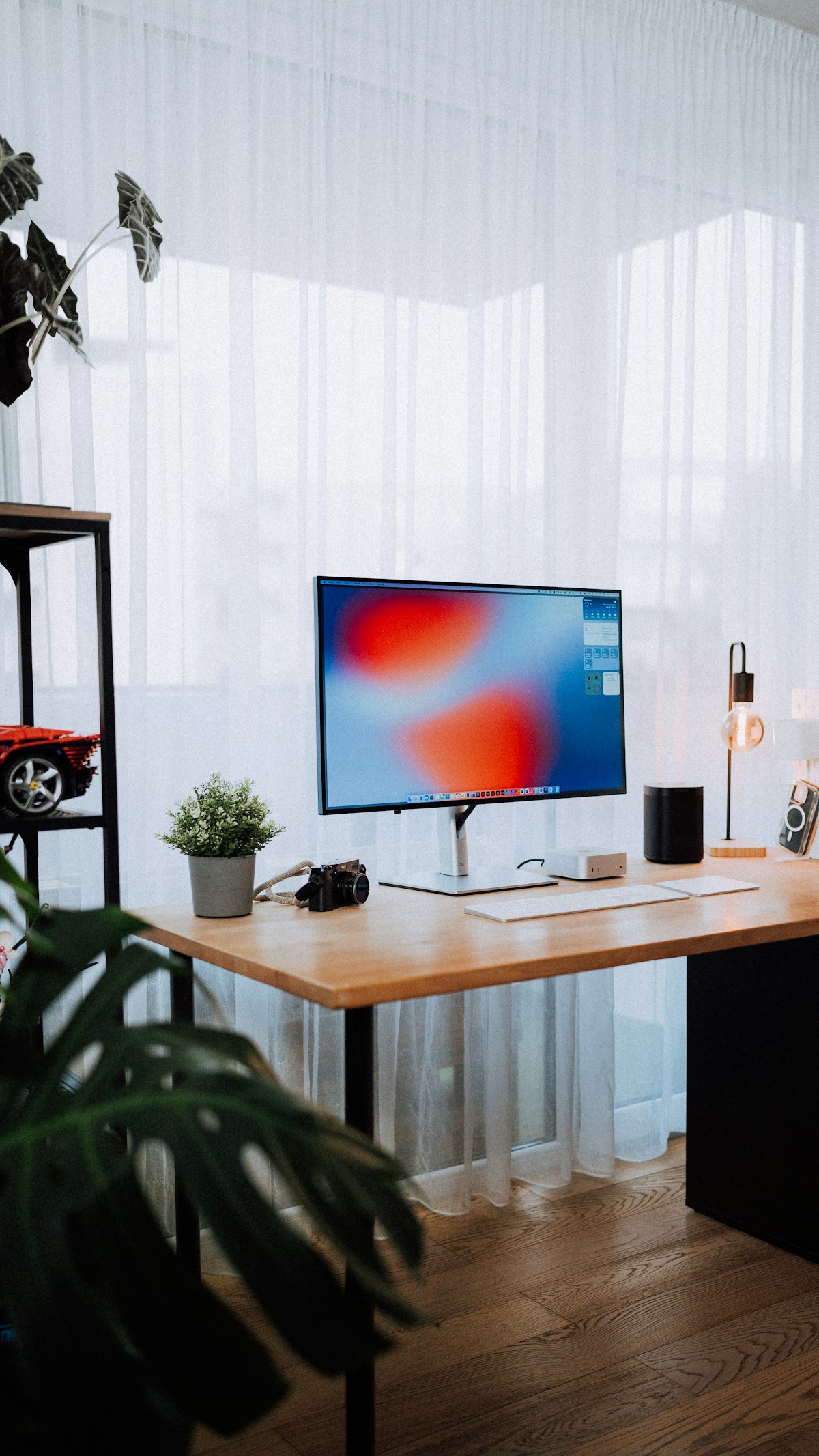 Cozy home office with modern desk setup featuring computer monitor and plant