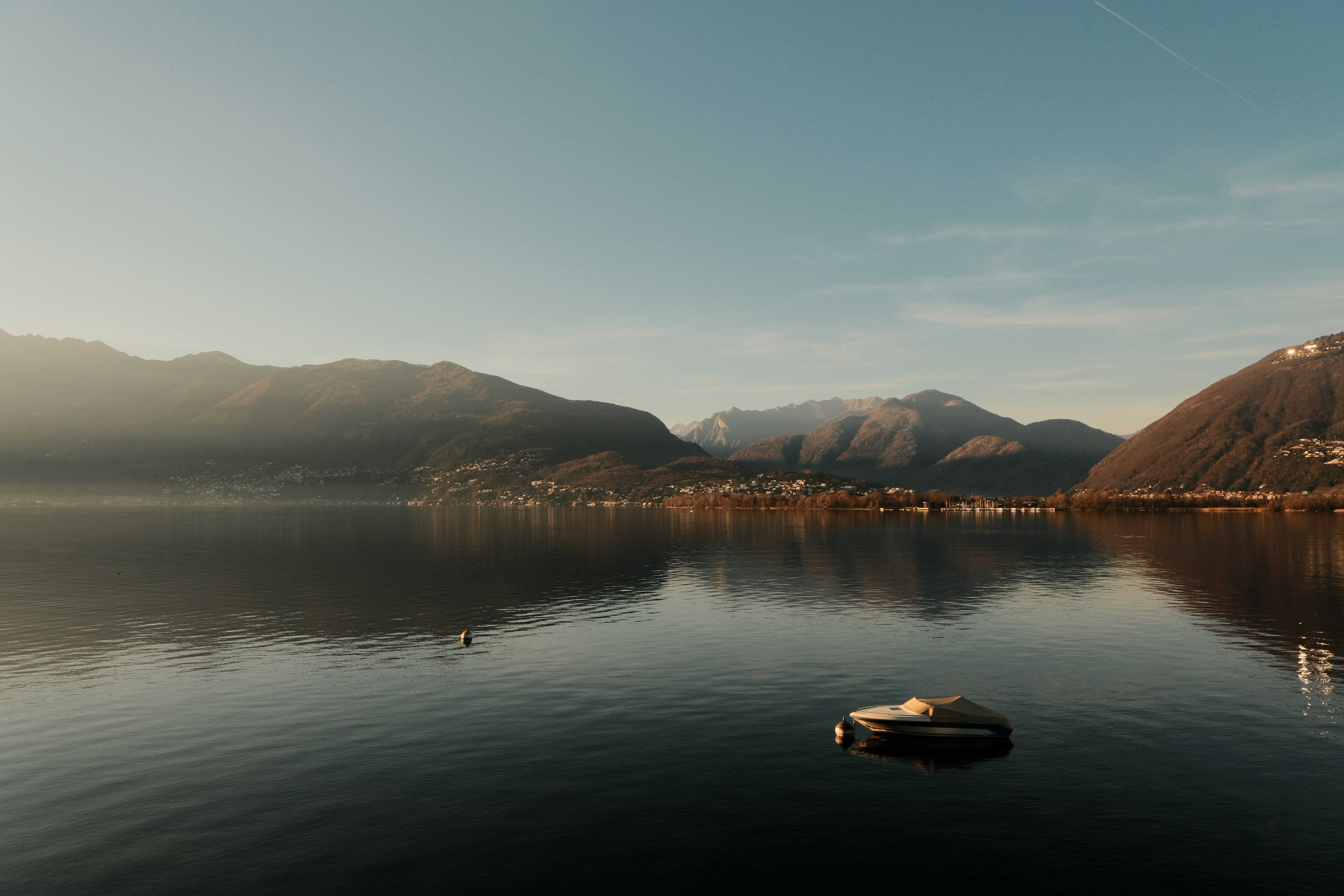 Serene lake scene with mountains under a blue sky.