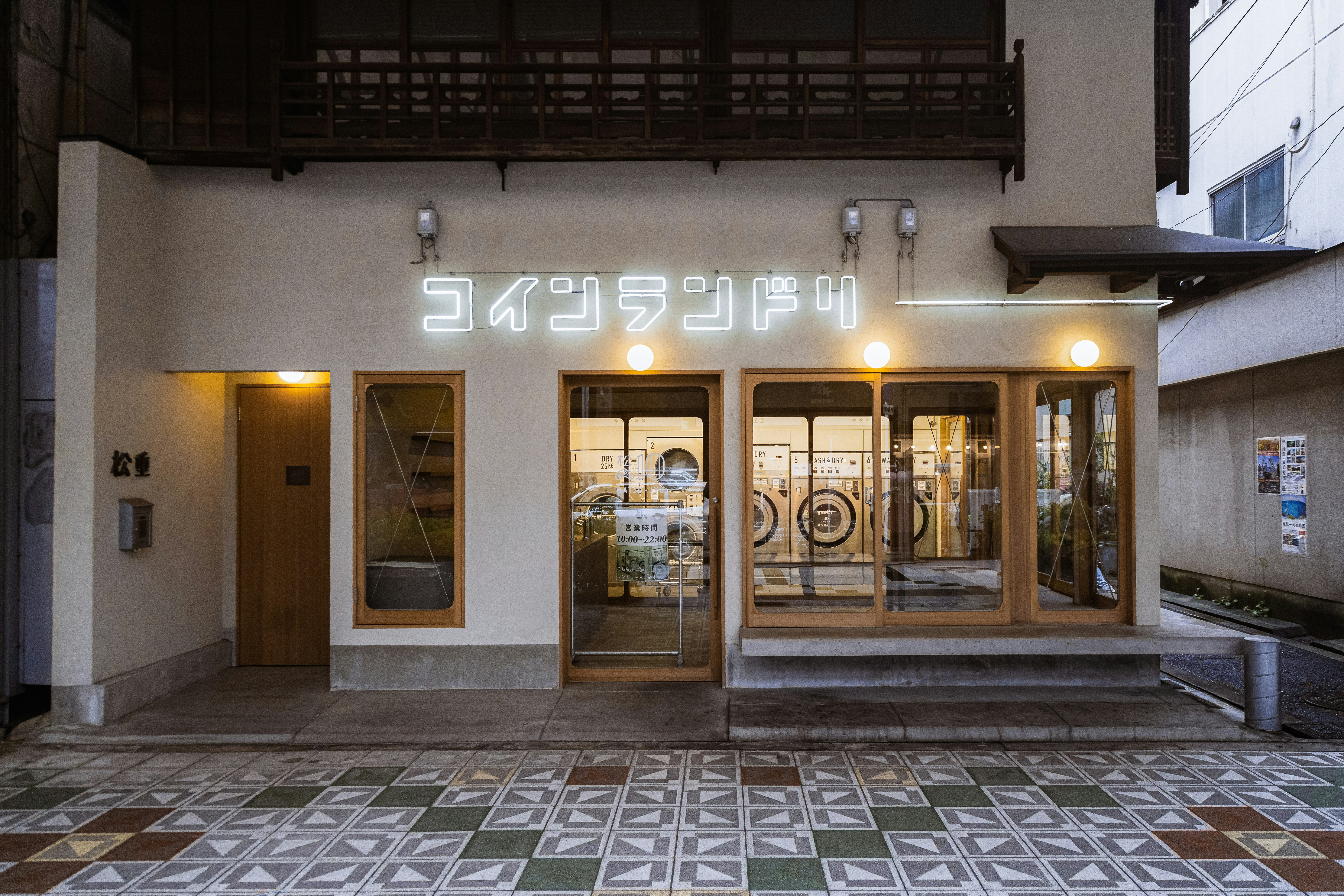 東京のコインランドリーの外観。白い建物に大きな窓と「コインランドリー」というネオン看板がある夜の写真。