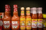 Shelf displays various bottles of hot sauce.