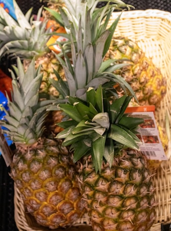Fresh pineapples are piled up in a basket.
