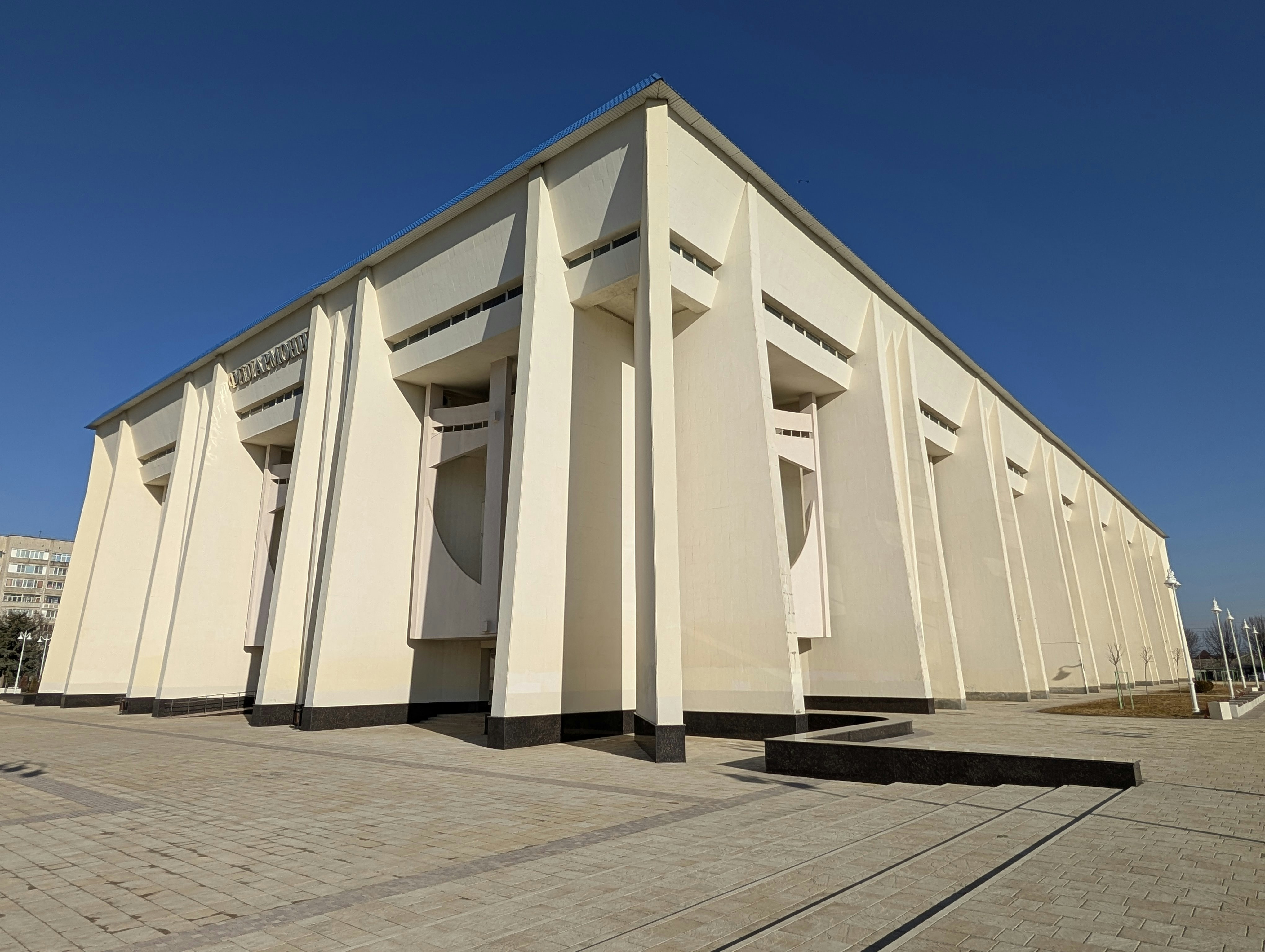 Modern, angular building stands against a bright blue sky.