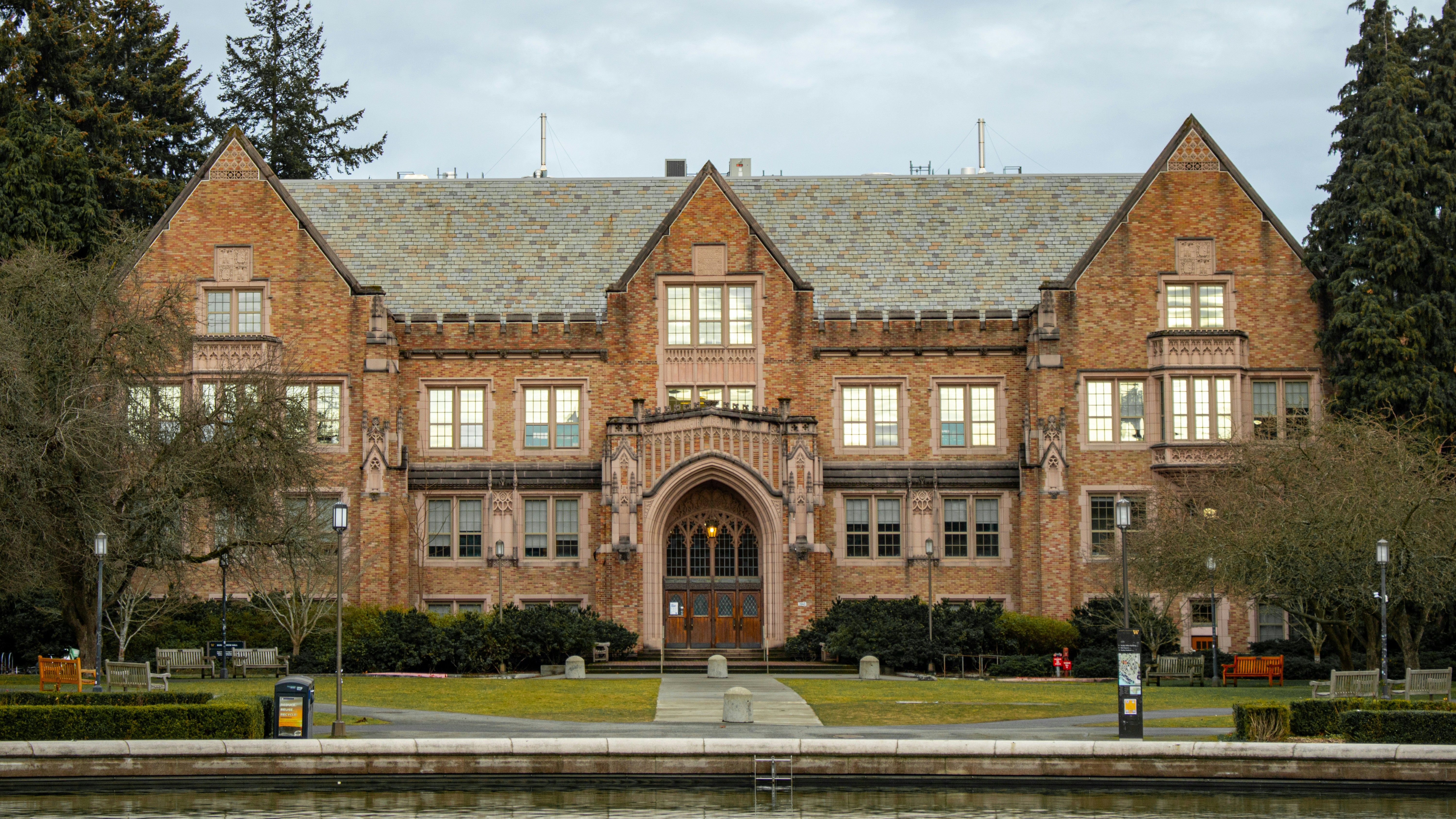 This image showcases Guggenheim Hall, a prominent landmark at the University of Washington. Built in 1930 and designed by John Graham, it's a distinctive example of Tudor Gothic architecture, with its brick facade, steep gables, and arched entryways. Funded by the Guggenheim Foundation, it was originally dedicated to aeronautical engineering, even boasting a high-tech lectern for faculty demonstrations. Today, Guggenheim Hall is home to the Department of Aeronautics u0026 Astronautics, continuing its legacy in aerospace studies.
