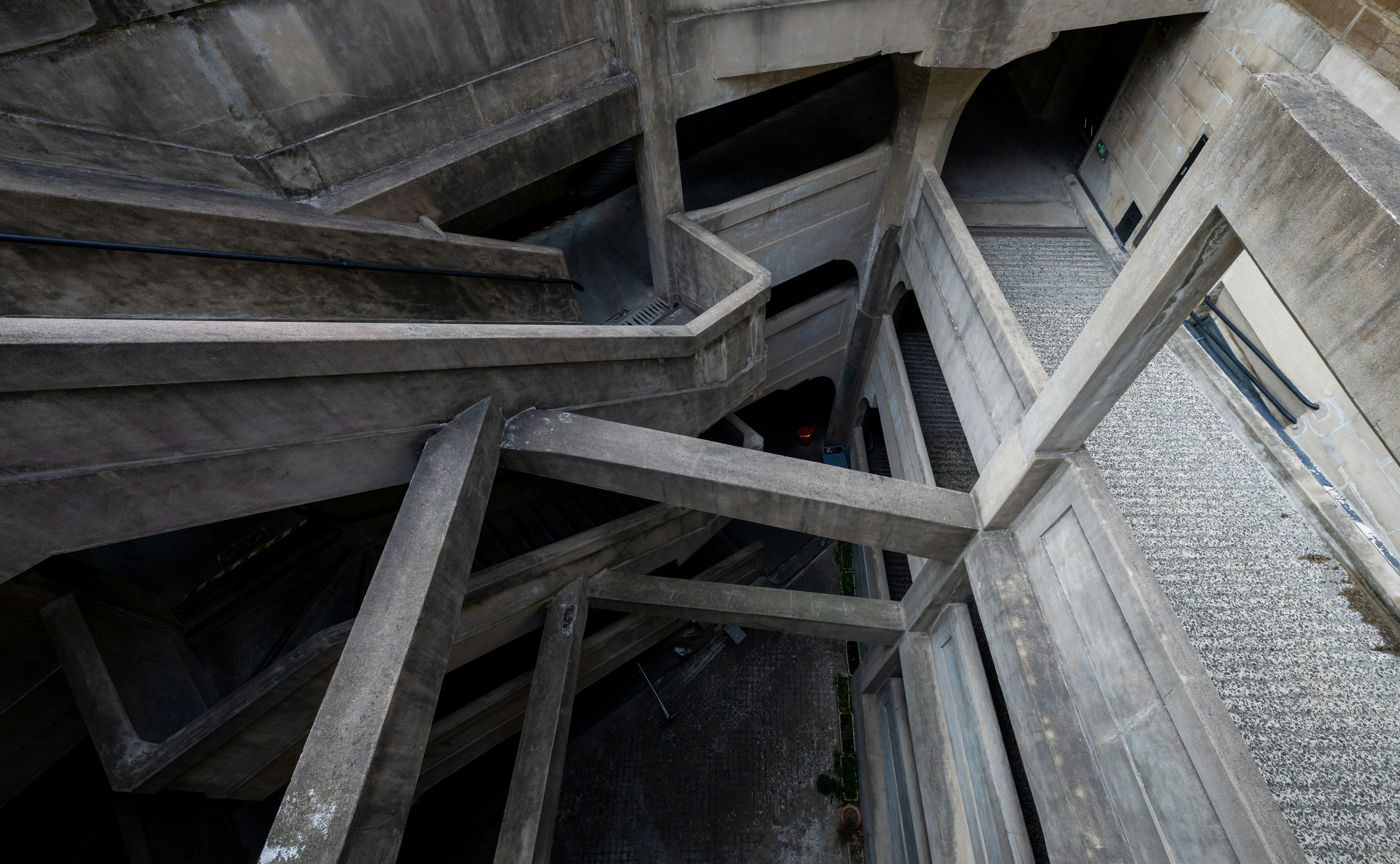 Concrete stairs spiral down inside a structure.