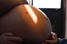 Pregnant woman's belly illuminated by sunlight.