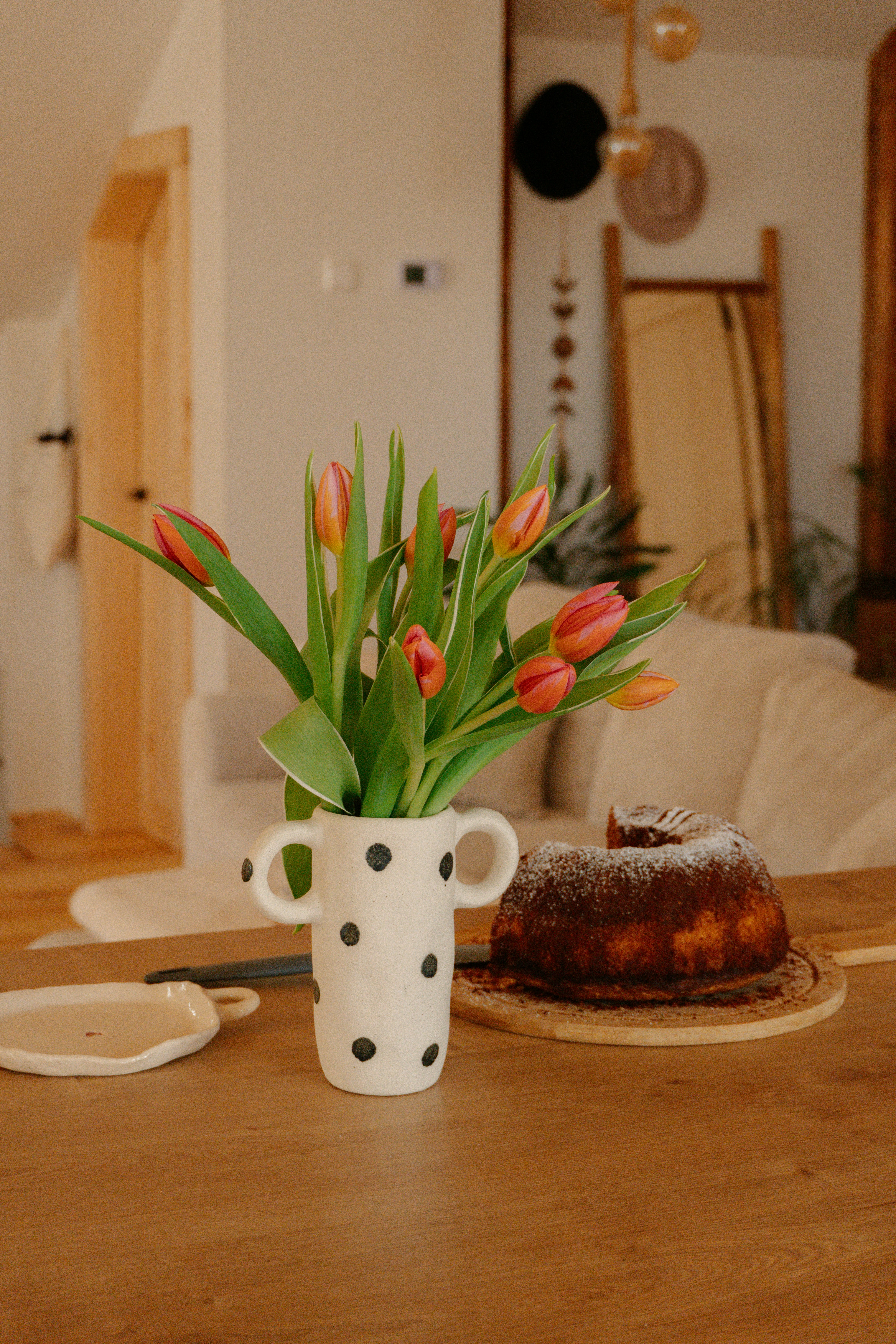 Tulips and cake adorn a cozy, bright dining table.