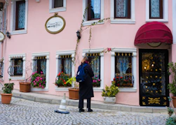 A person stands outside a pink building.