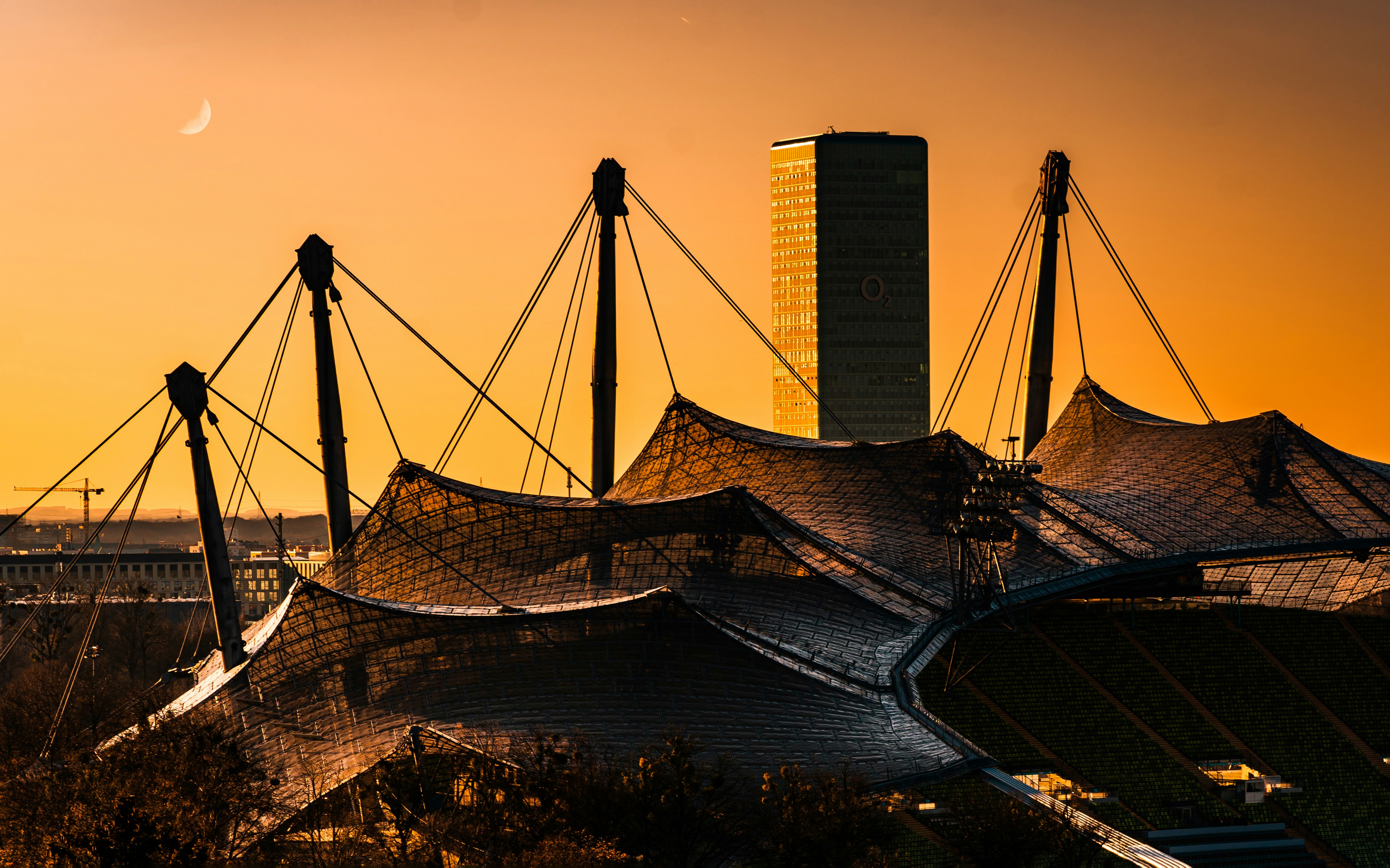 Olympic stadium in munich at sunset with a crescent moon.