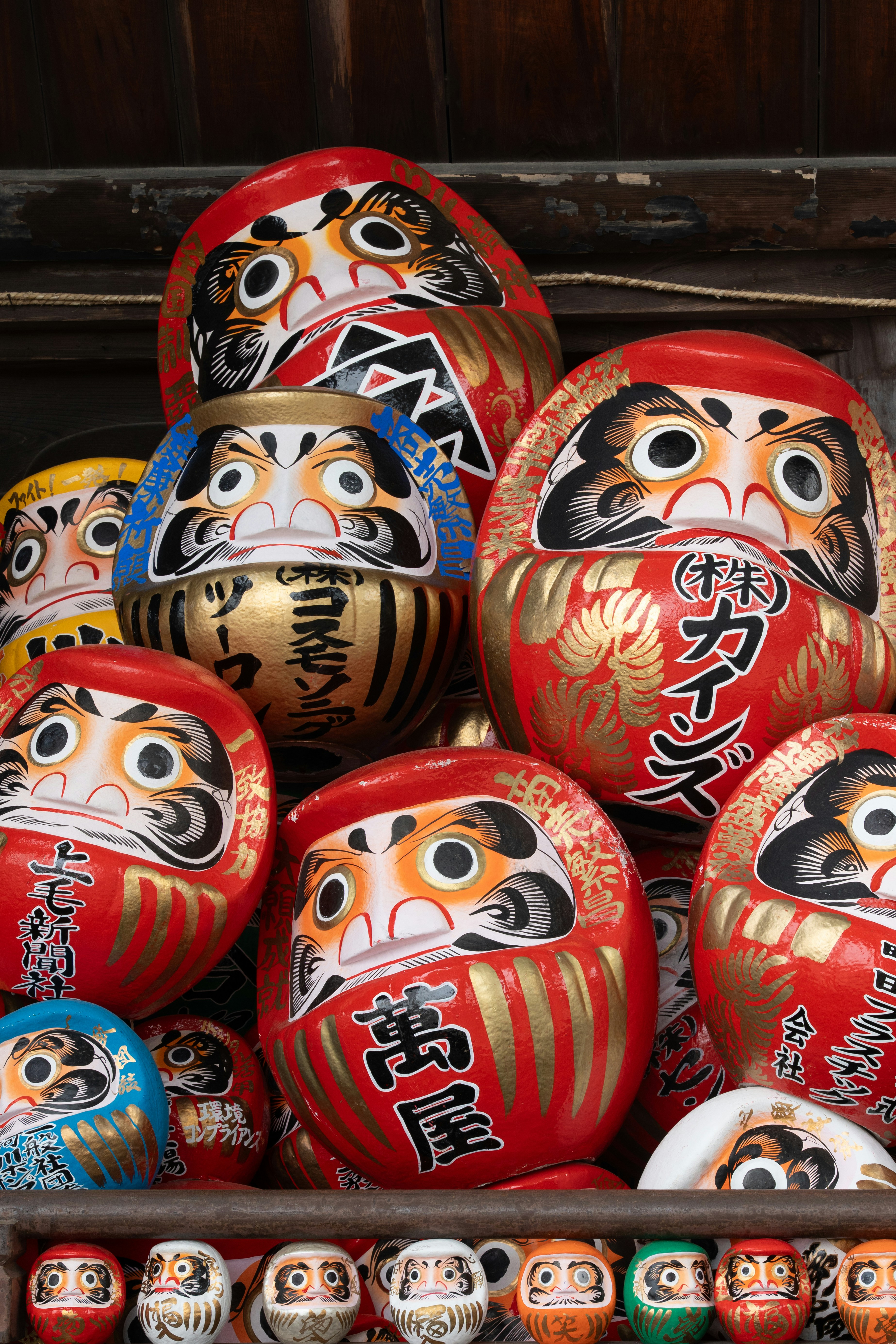 Many japanese daruma dolls are stacked together.