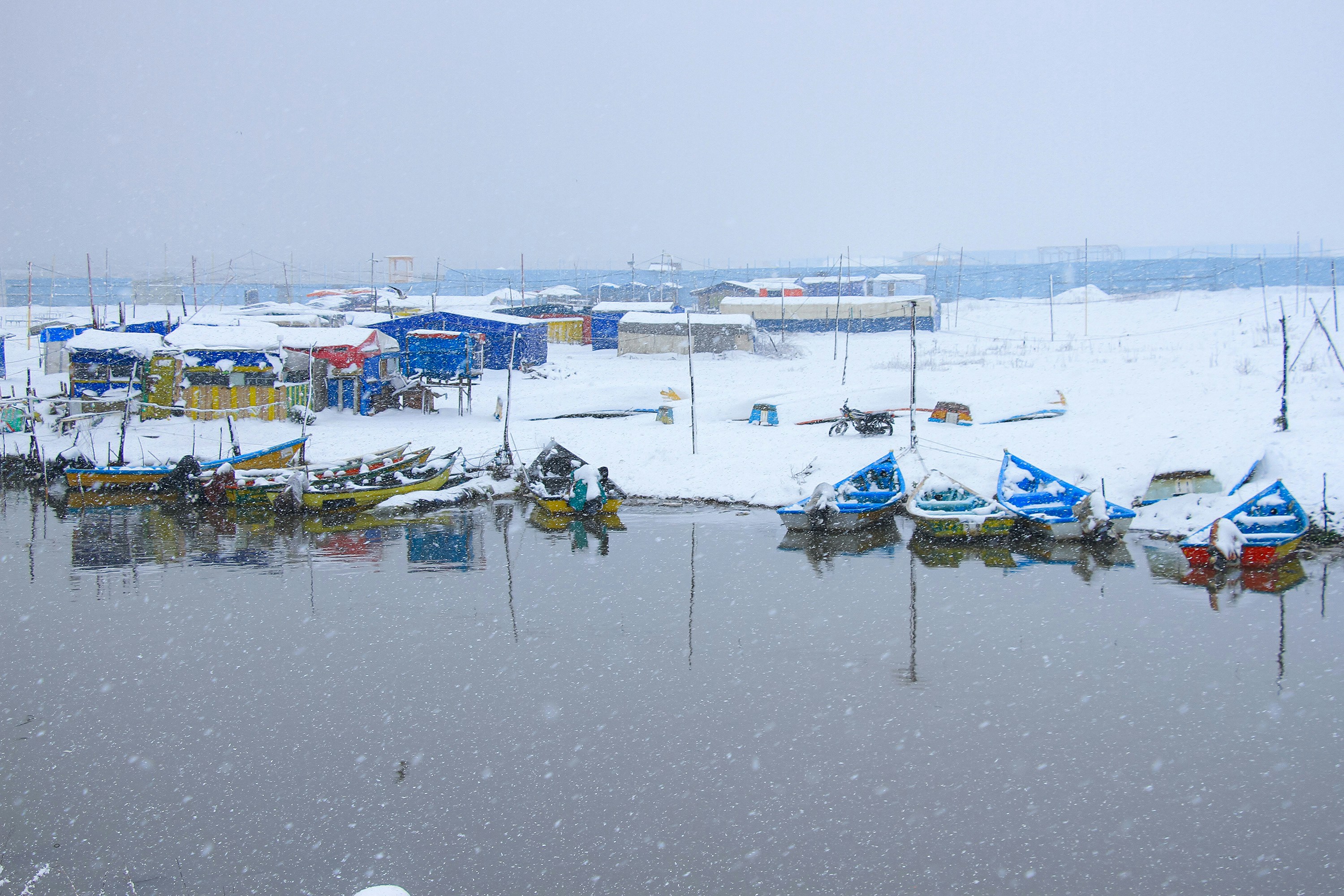 Boats are docked in a snowy harbor.