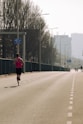A lone runner sprints down a long, empty road.