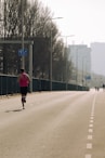A lone runner sprints down a long, empty road.