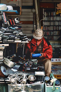 A man repairs electronics at a cluttered shop