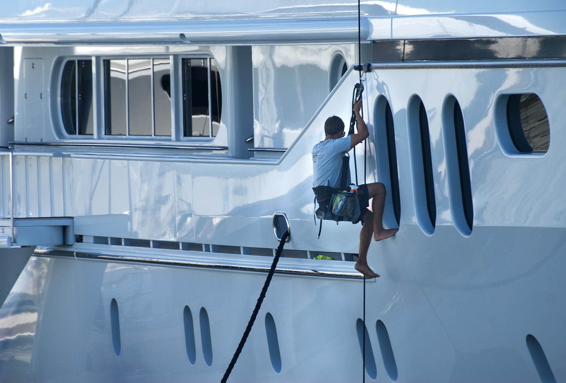 A man is climbing the side of a yacht.