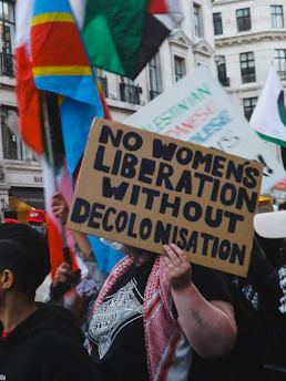 Protesters hold signs about decolonization and liberation.