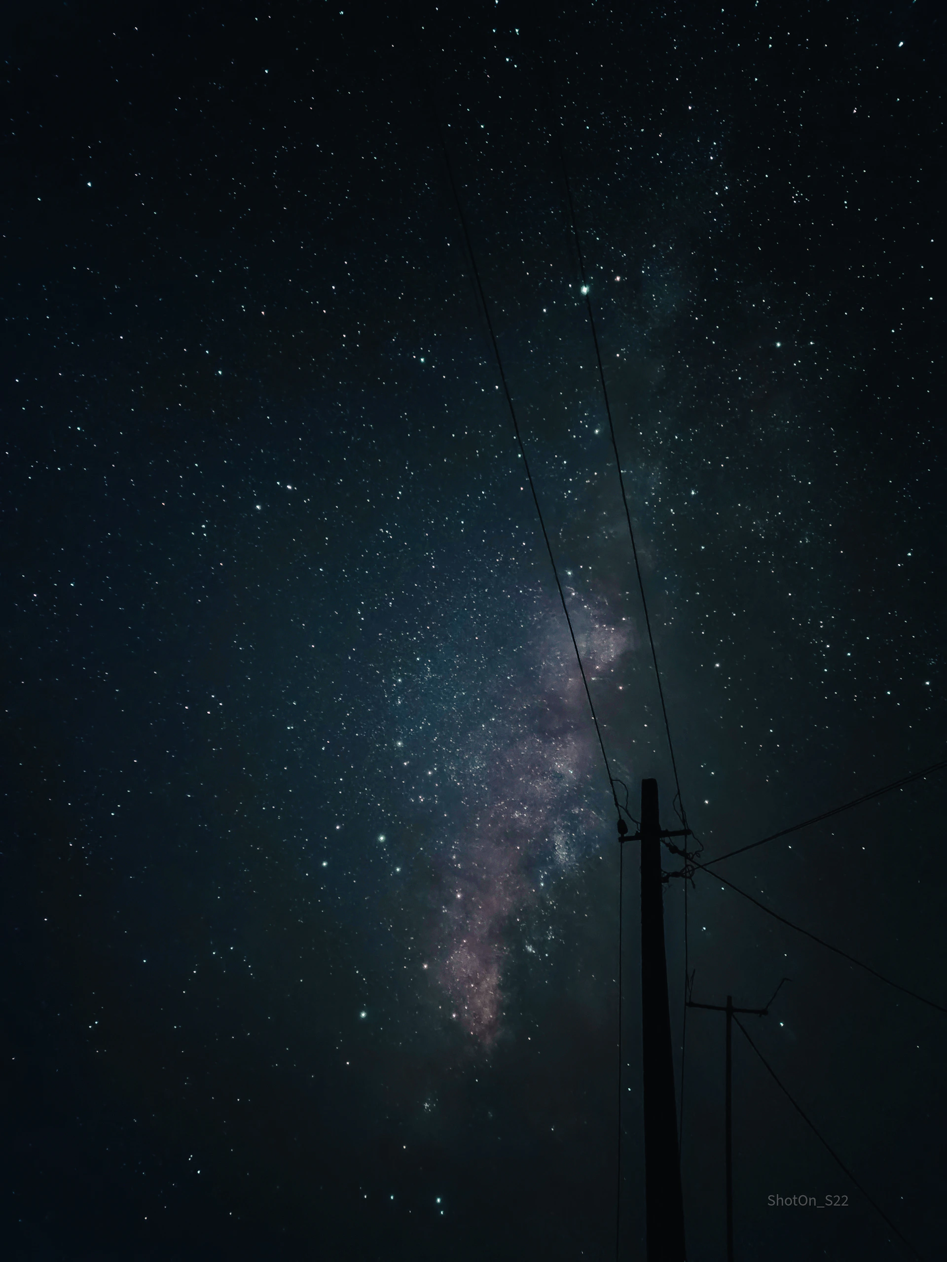 The milky way sparkles brilliantly above a power line.