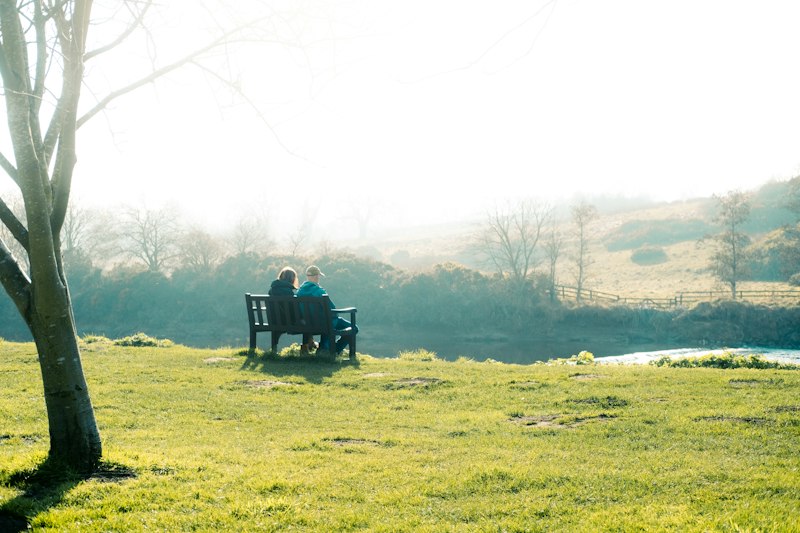 Couple sitting on a bench, overlooking nature.