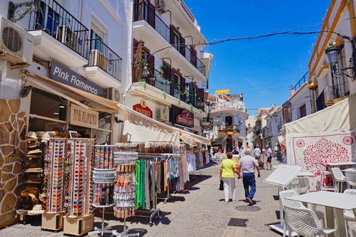 A sunny street lined with shops and people.