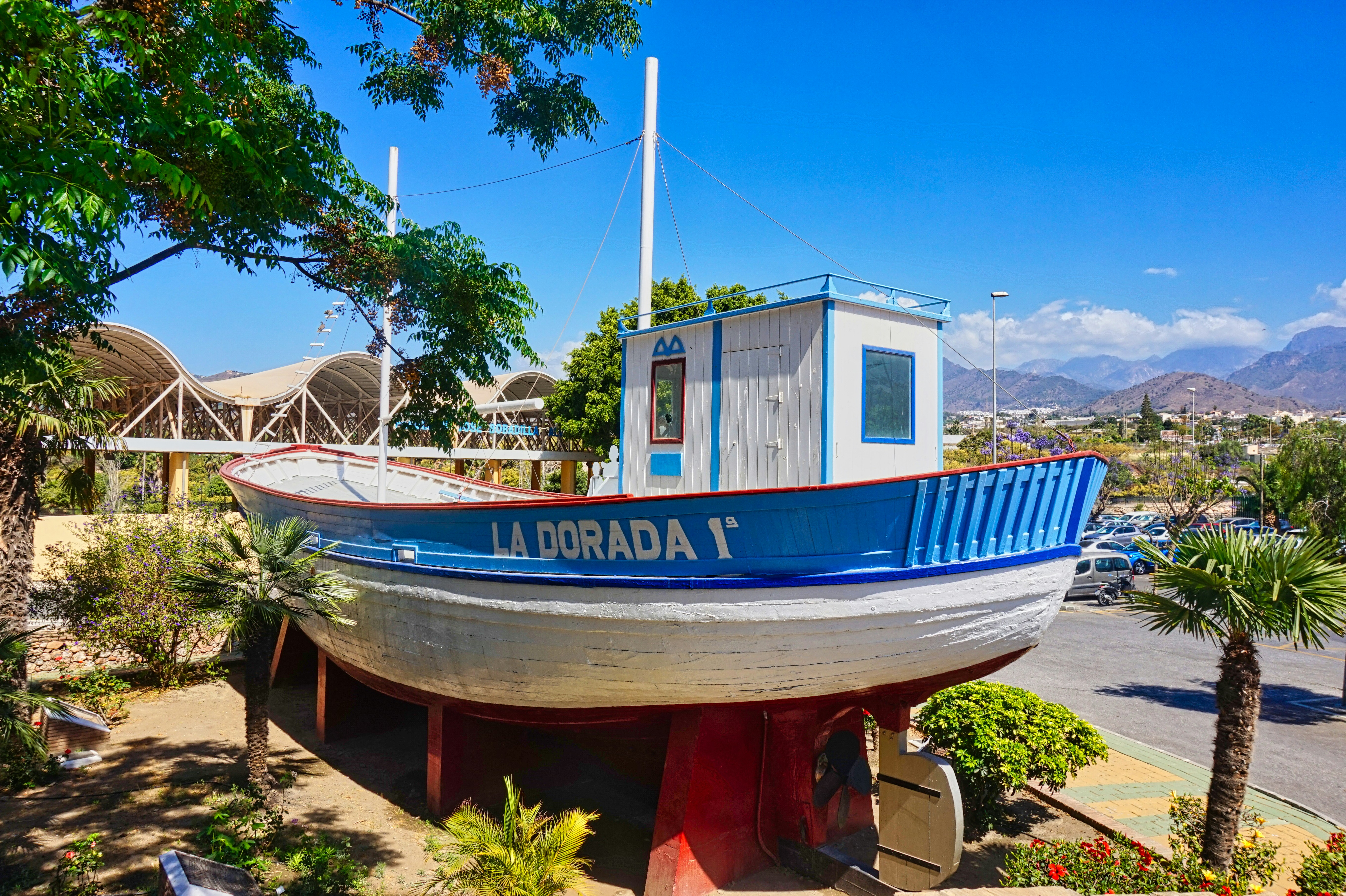 Ein Boot, das an Land in einer sonnigen Umgebung ausgestellt ist.