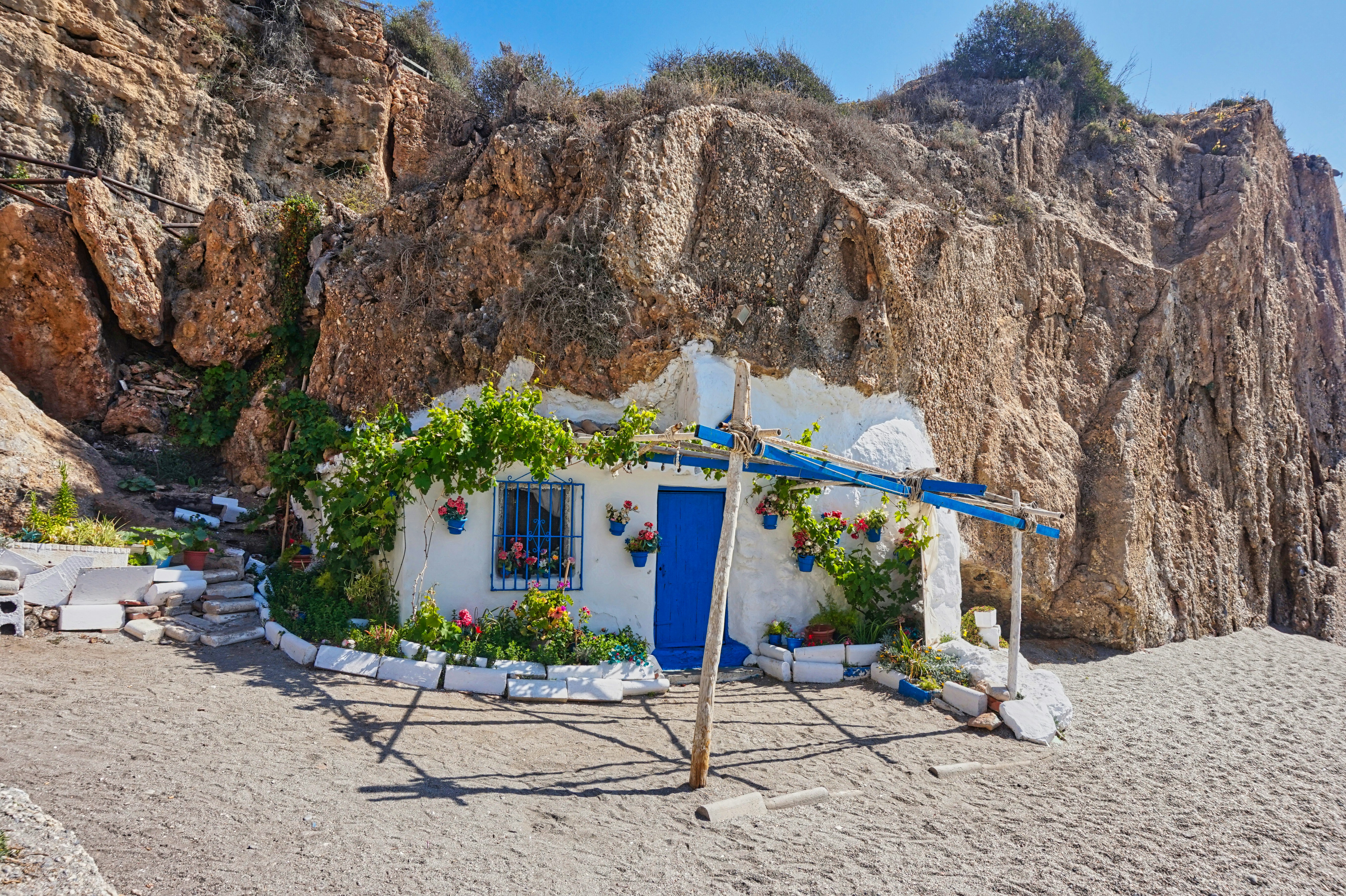 Ein kleines Ferienhaus liegt an einem Strand an einer Klippe.