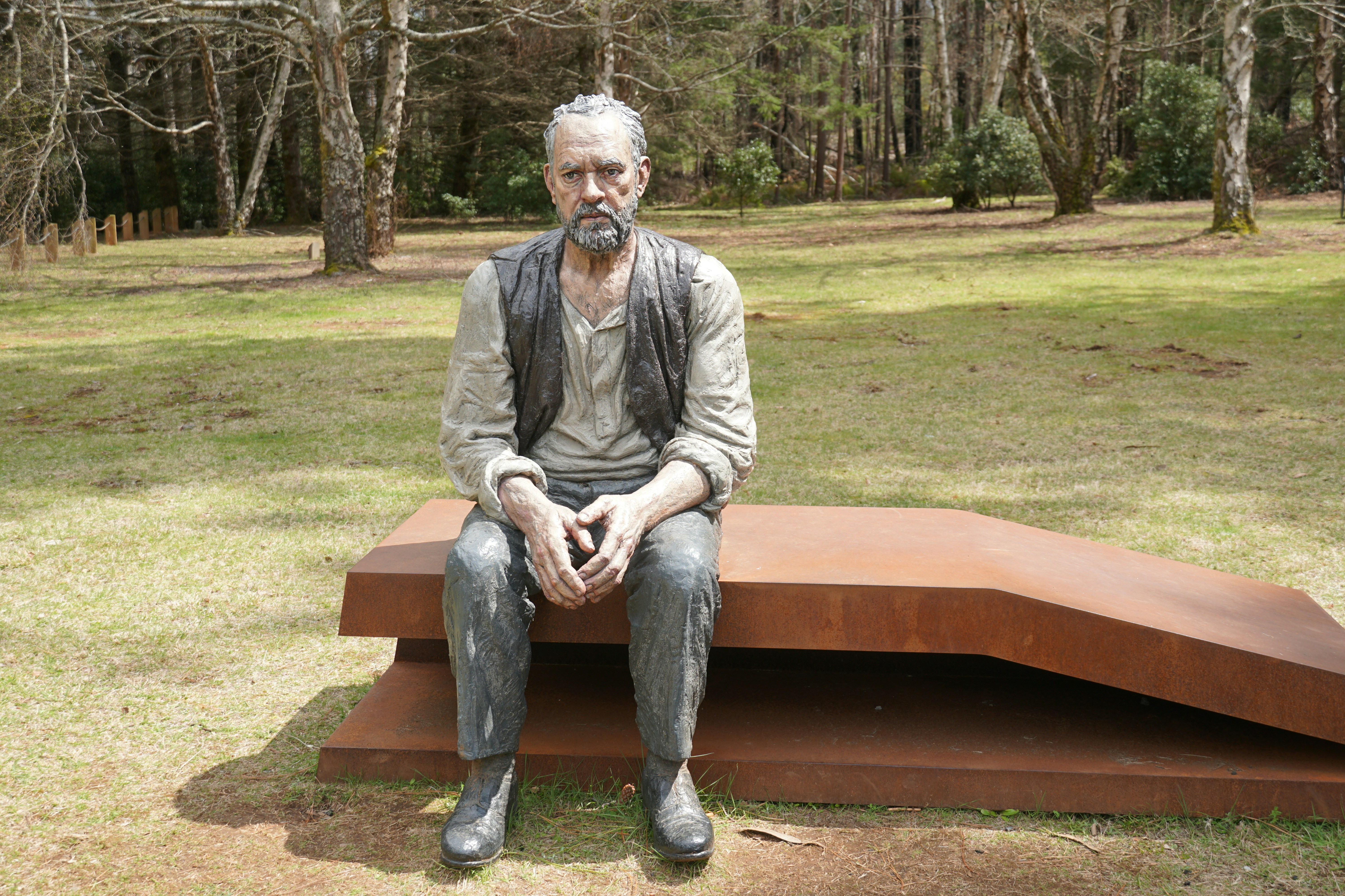 A statue of a man sitting on a bench.