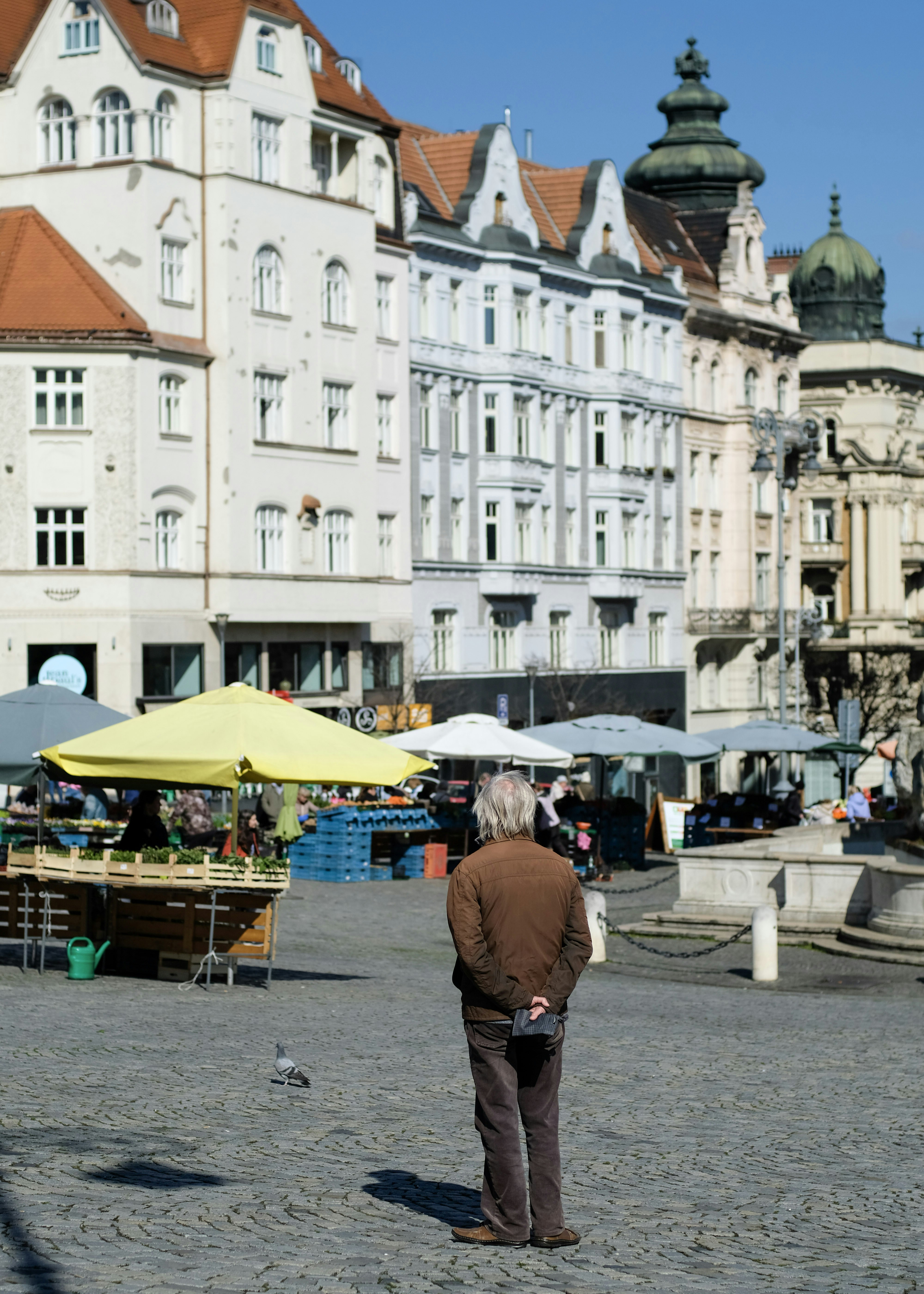 A man stands in a european town square.