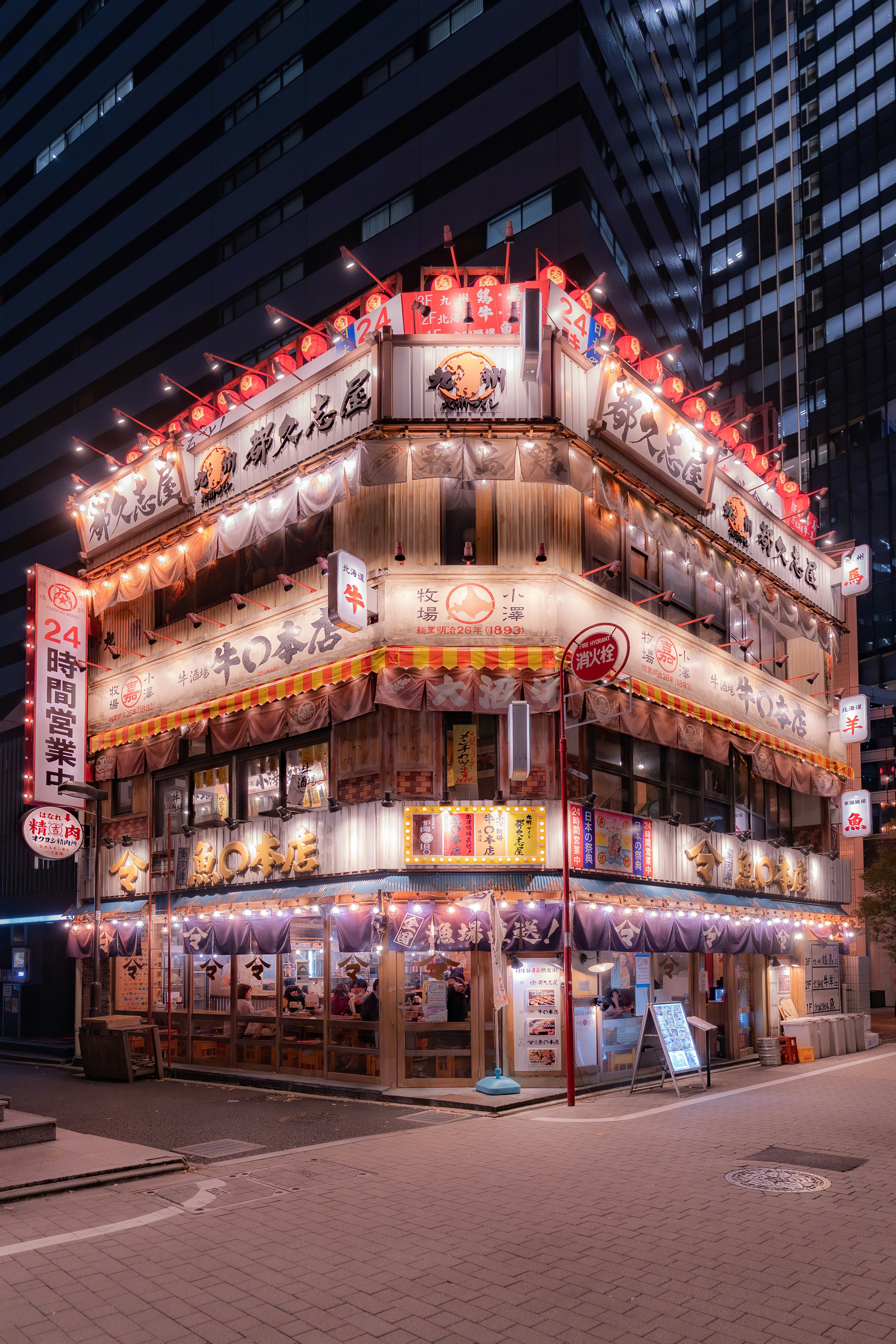 A japanese restaurant lights up a city corner.