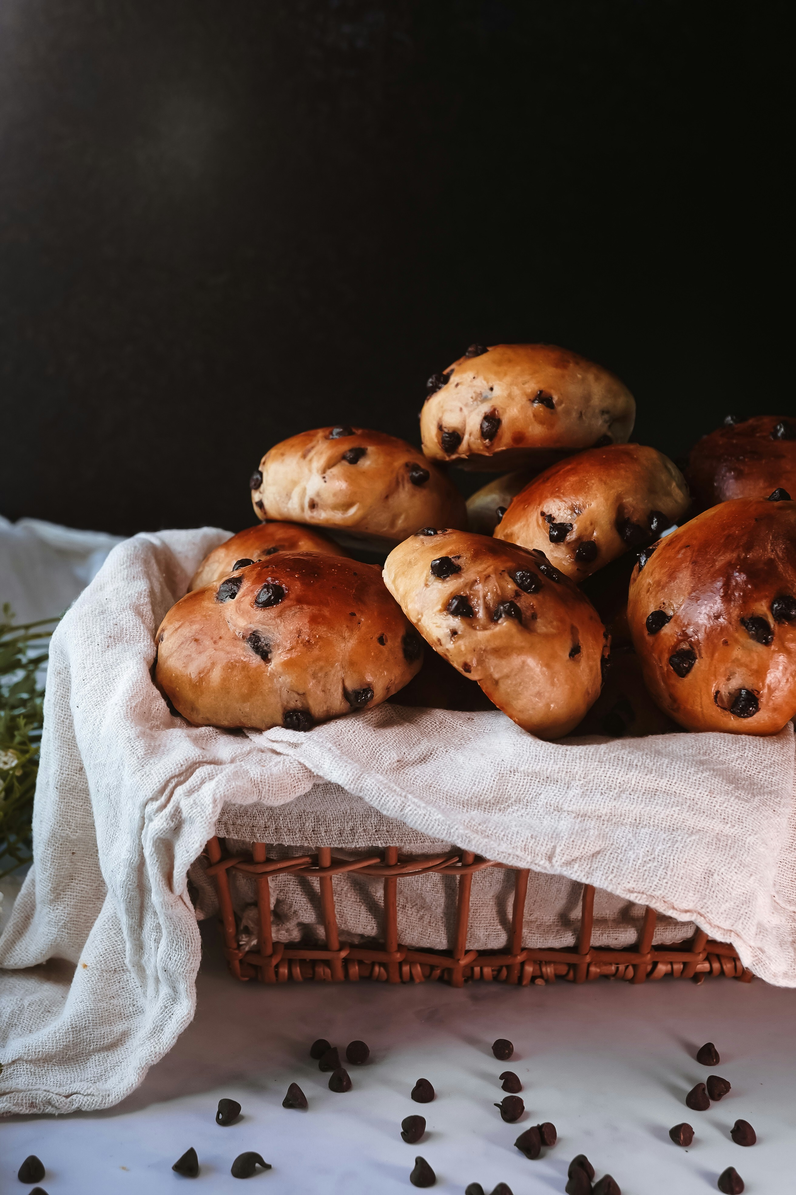 Chocolate chip buns are arranged in a rustic basket.