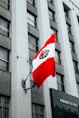 The peruvian flag hangs on a building's wall.
