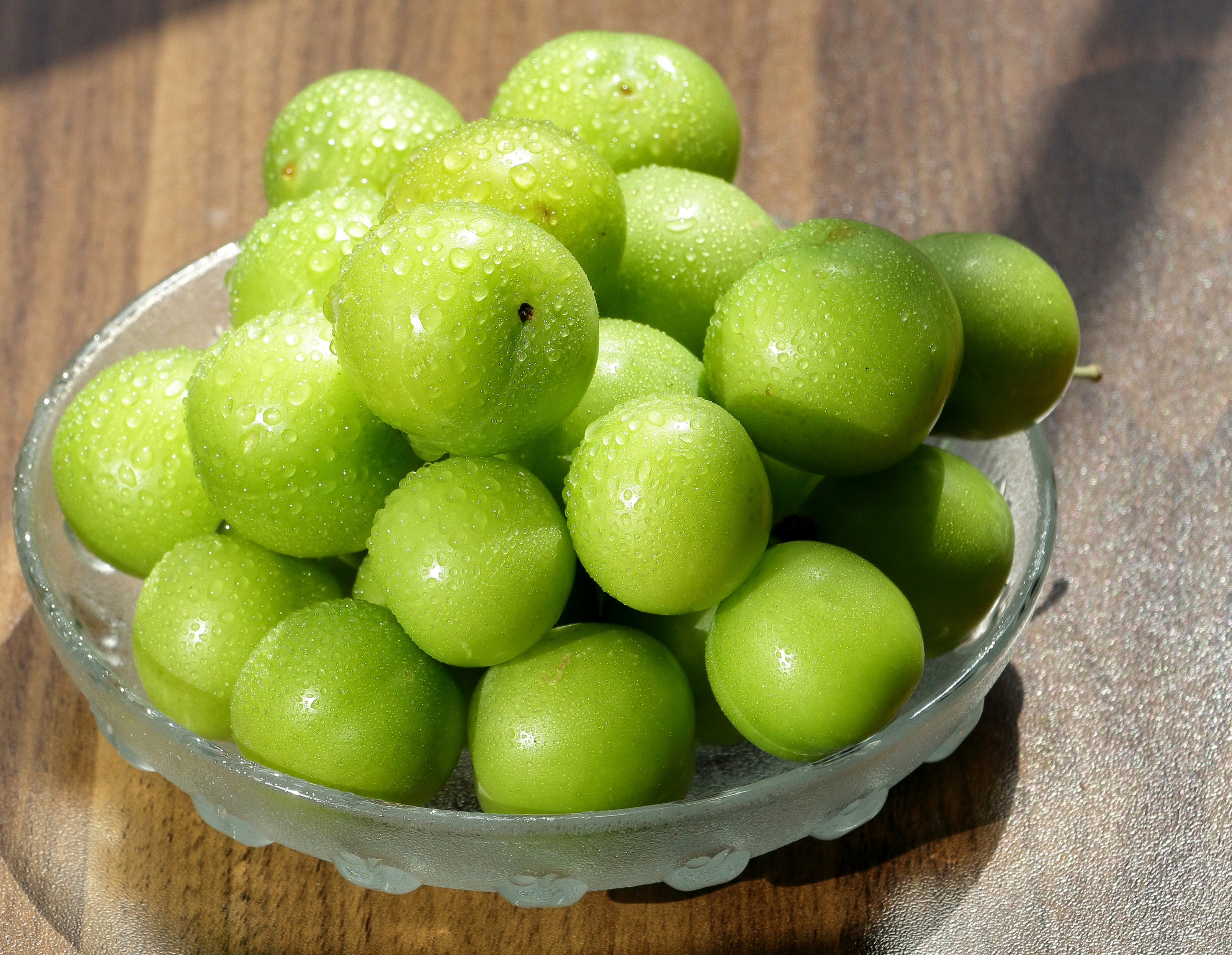 Semangkuk plum hijau segar ditampilkan.