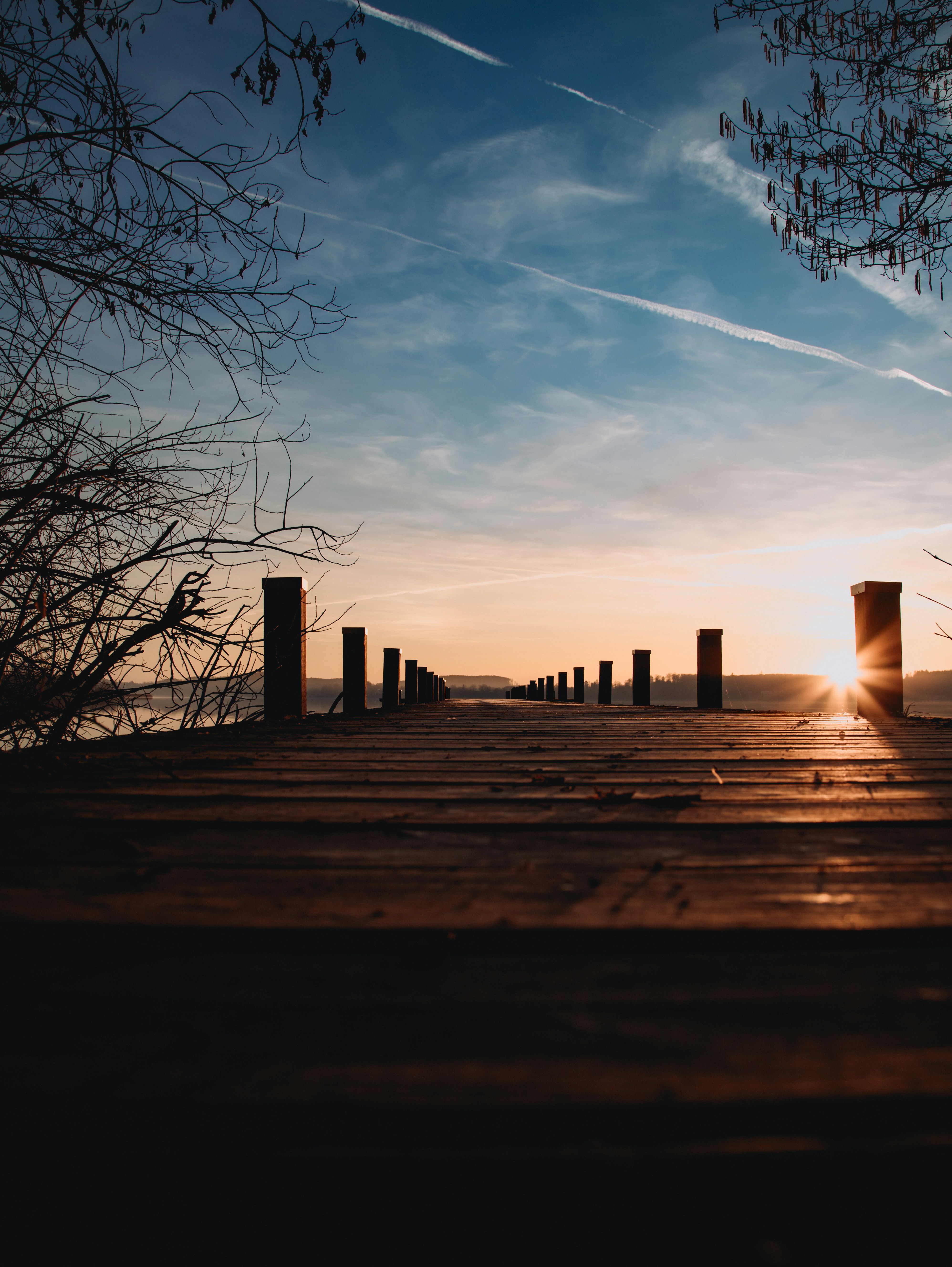 Sunset shines from the end of a pier.