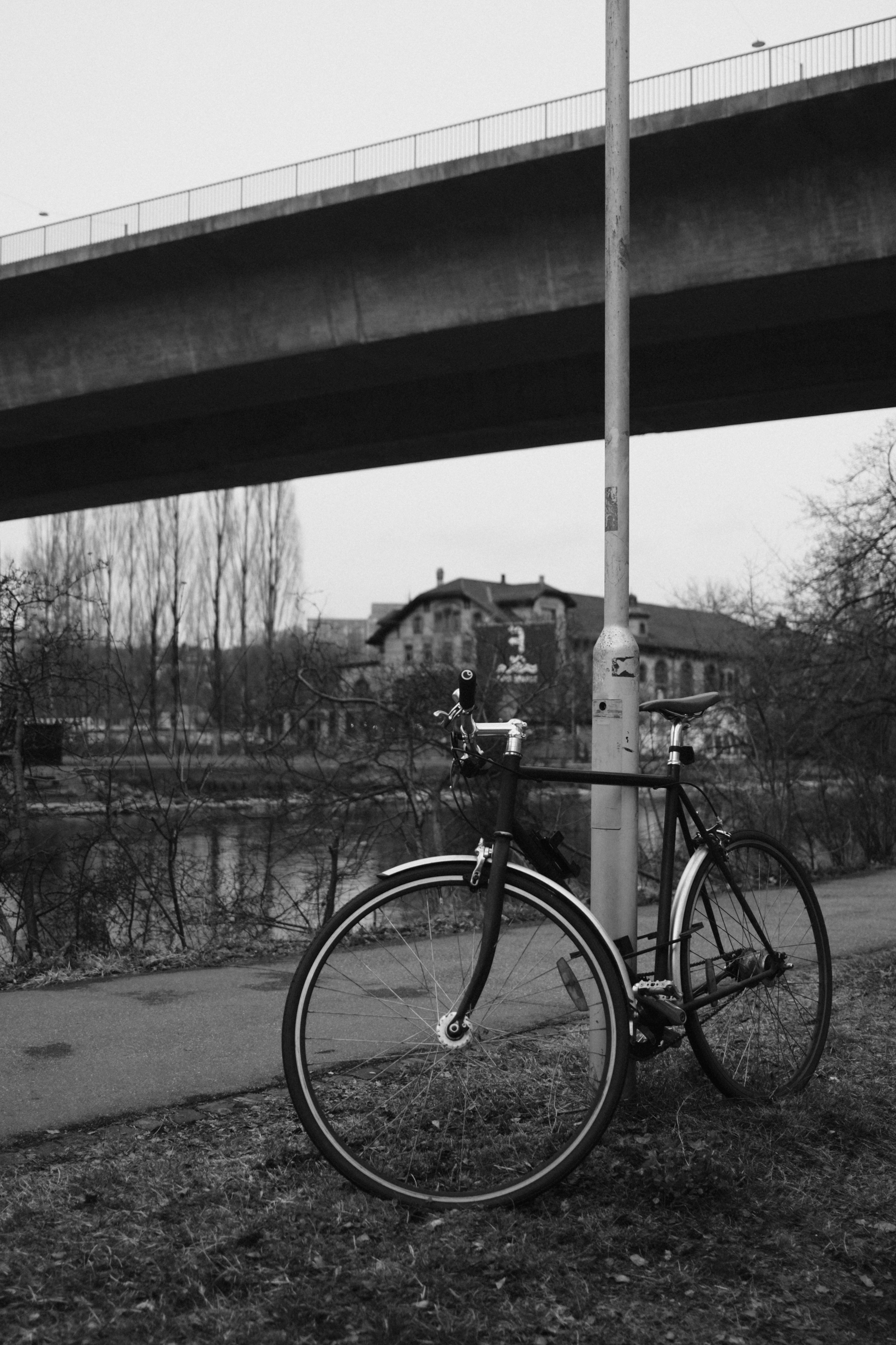 La bicicleta se apoya en un poste debajo de un puente.