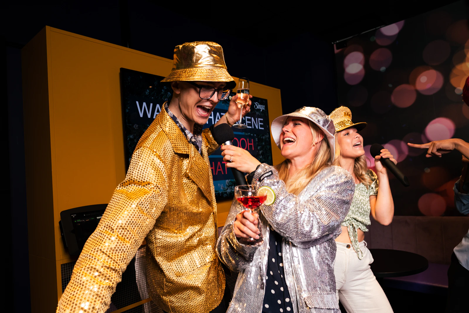 Coworkers singing karaoke together with microphones at a company party