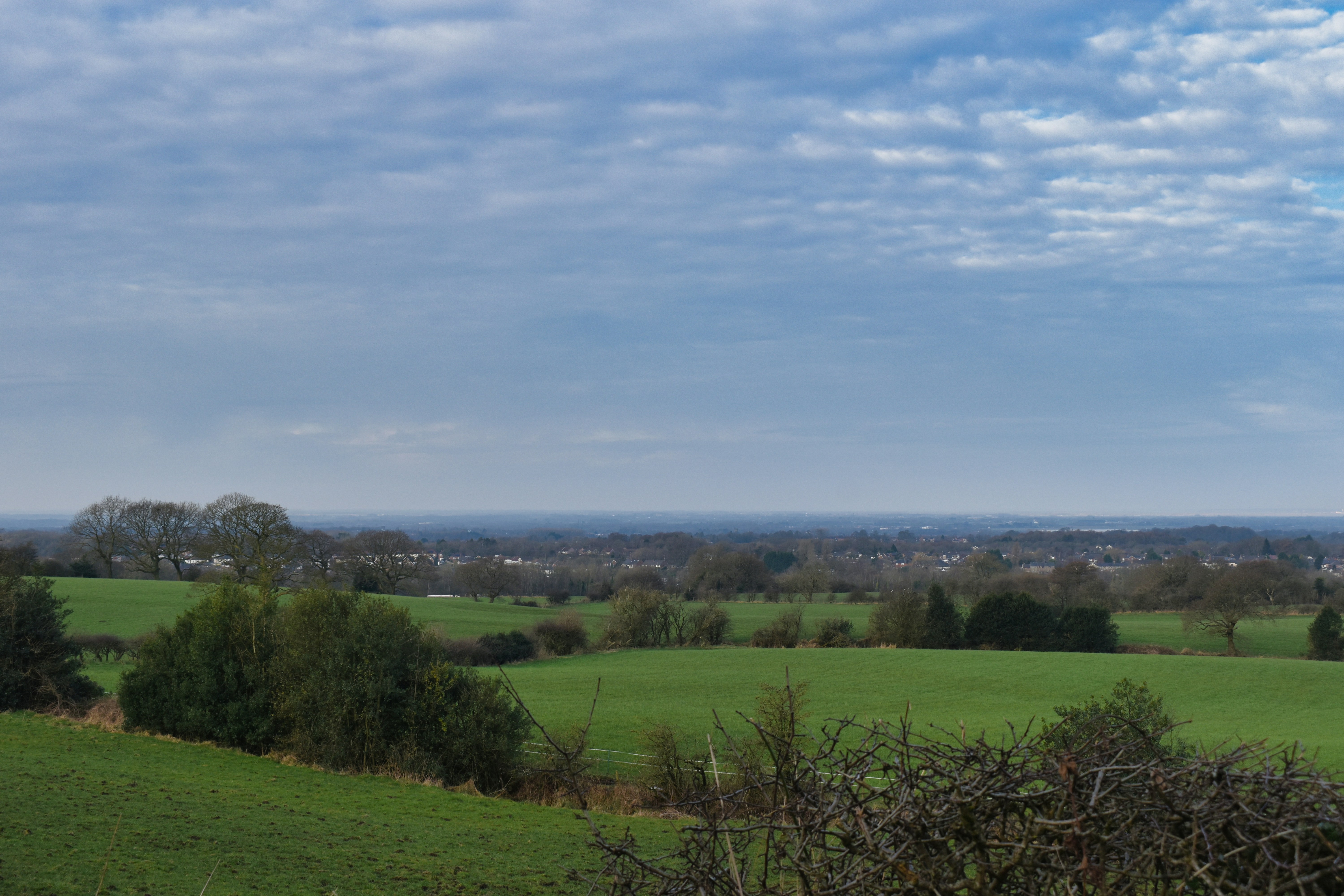 Rolling green fields are under a cloudy sky.