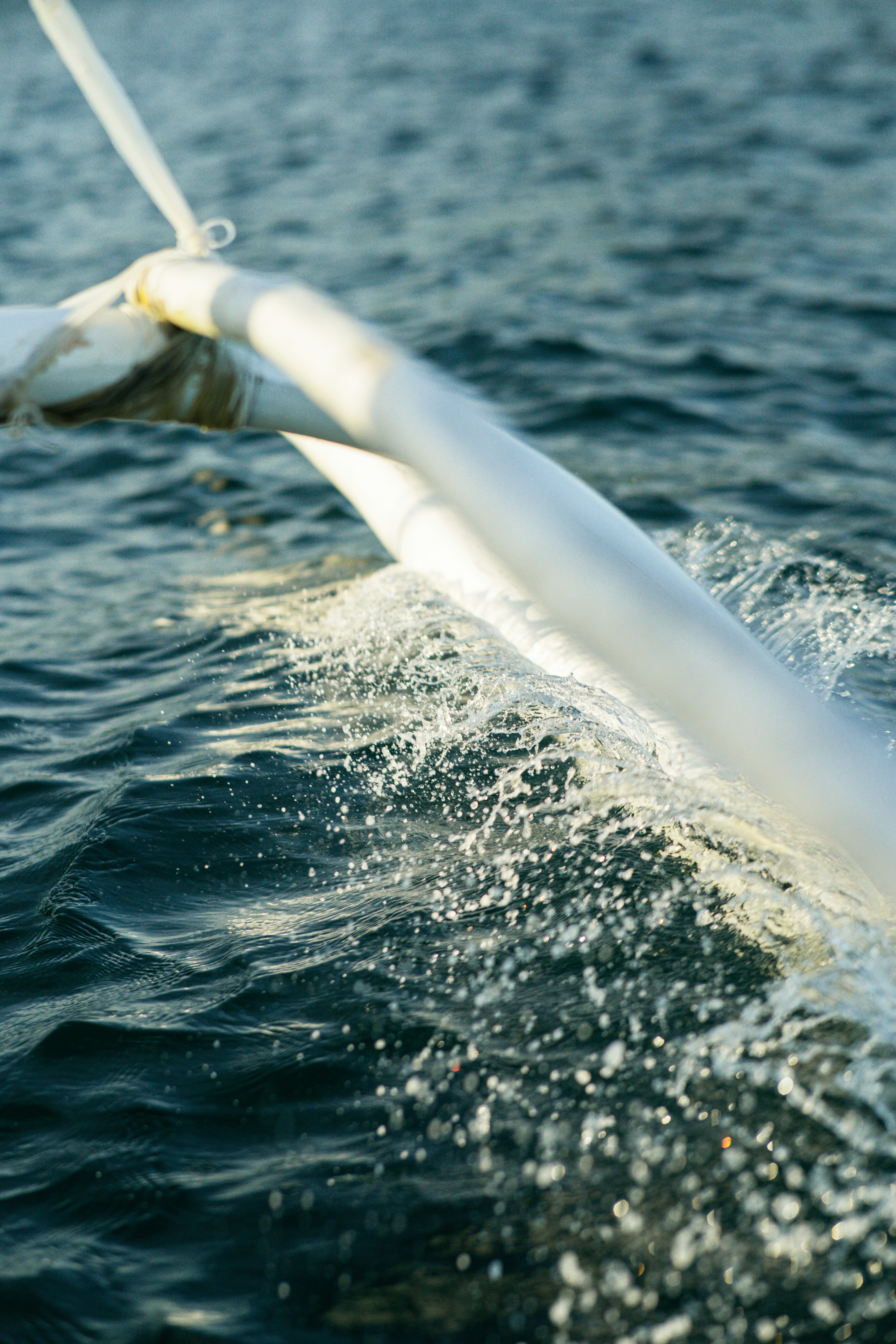 Sailing on the water, creating splashes and waves.