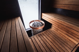 A cozy sauna with wooden benches and rocks.