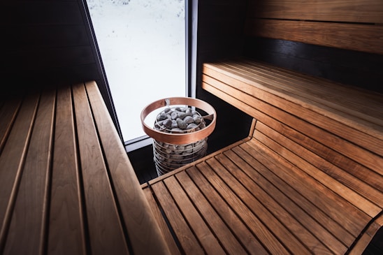 A cozy sauna with wooden benches and rocks.