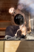 A man pours water on hot sauna rocks.
