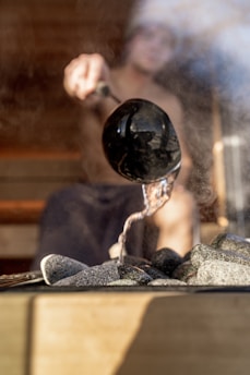 A man pours water on hot sauna rocks.