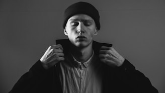 Man adjusting coat collar, monochrome portrait.