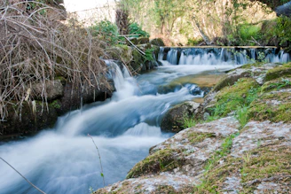 A stream cascades over rocks in a scenic landscape.