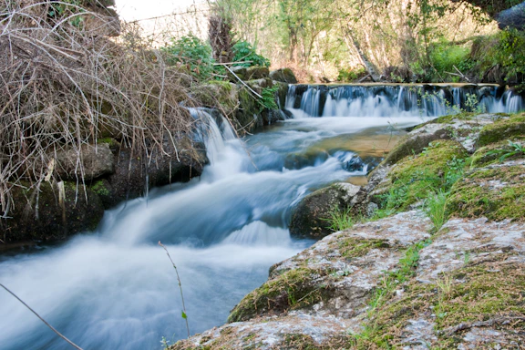 A stream cascades over rocks in a scenic landscape.