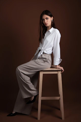 Woman poses on a stool in a brown studio.