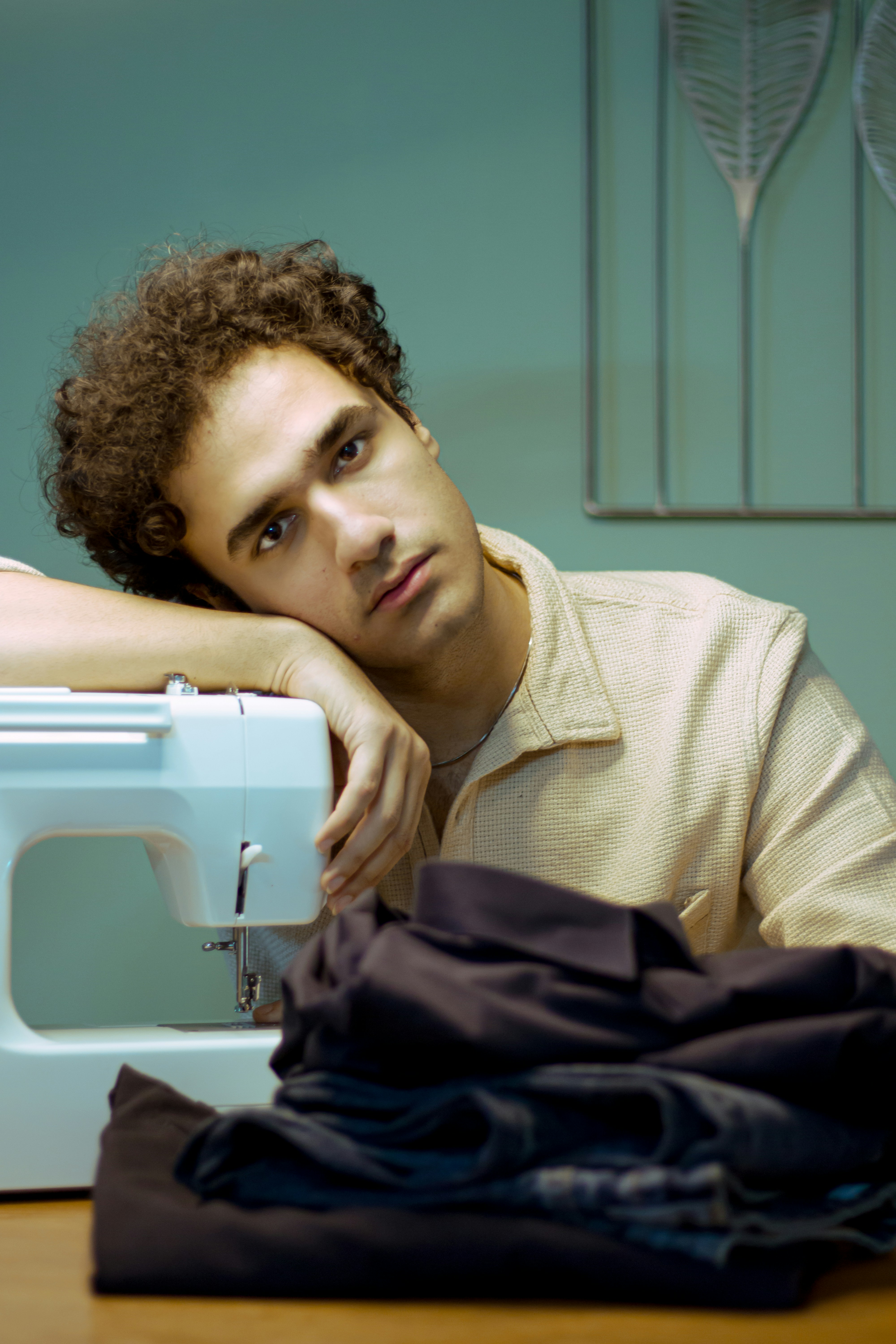 Mann sieht müde aus, während er mit der Maschine näht.