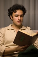 Man with curly hair is reading a book.