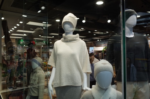 Clothing mannequins are displayed in a store window.