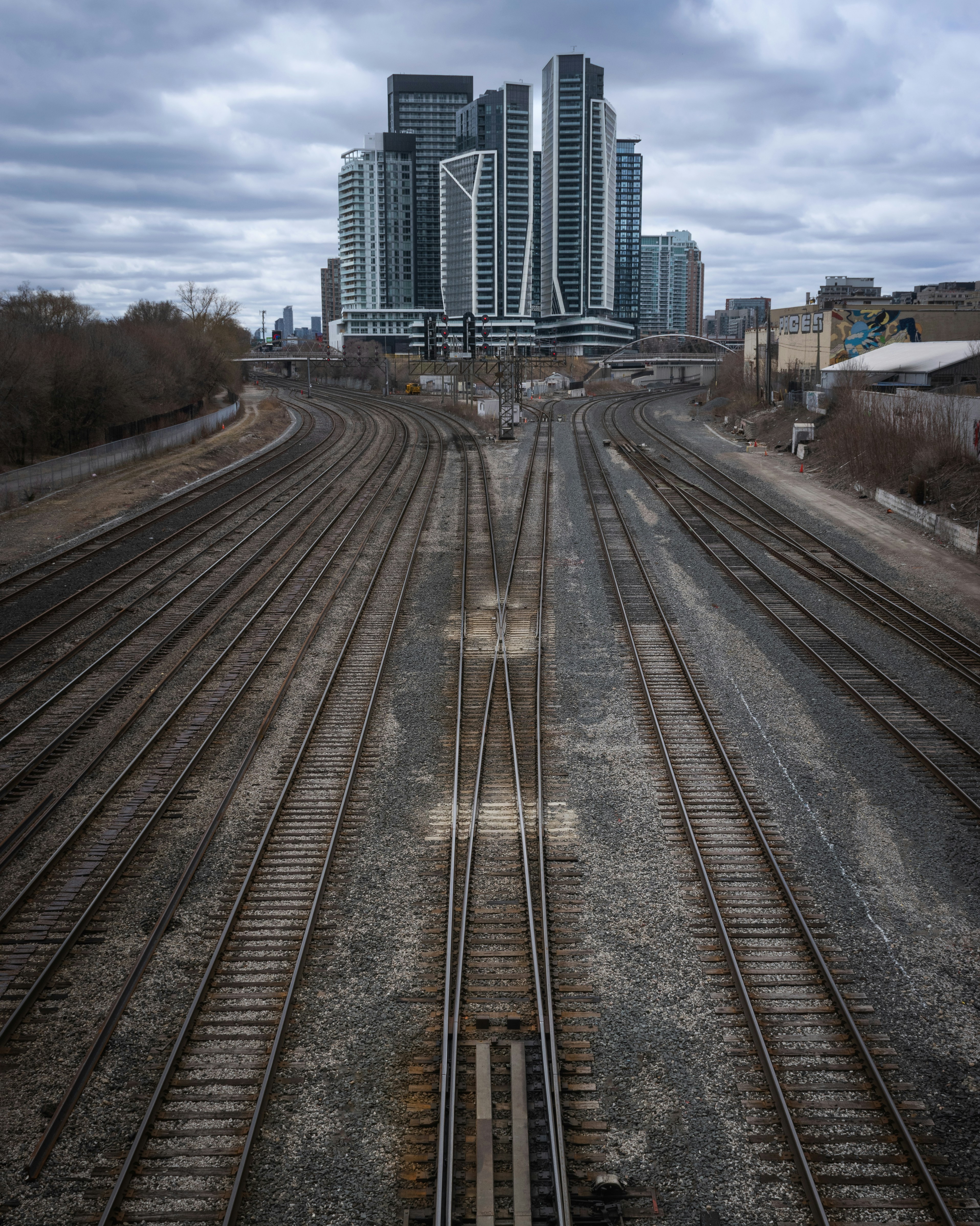 City skyscrapers rise behind converging train tracks.