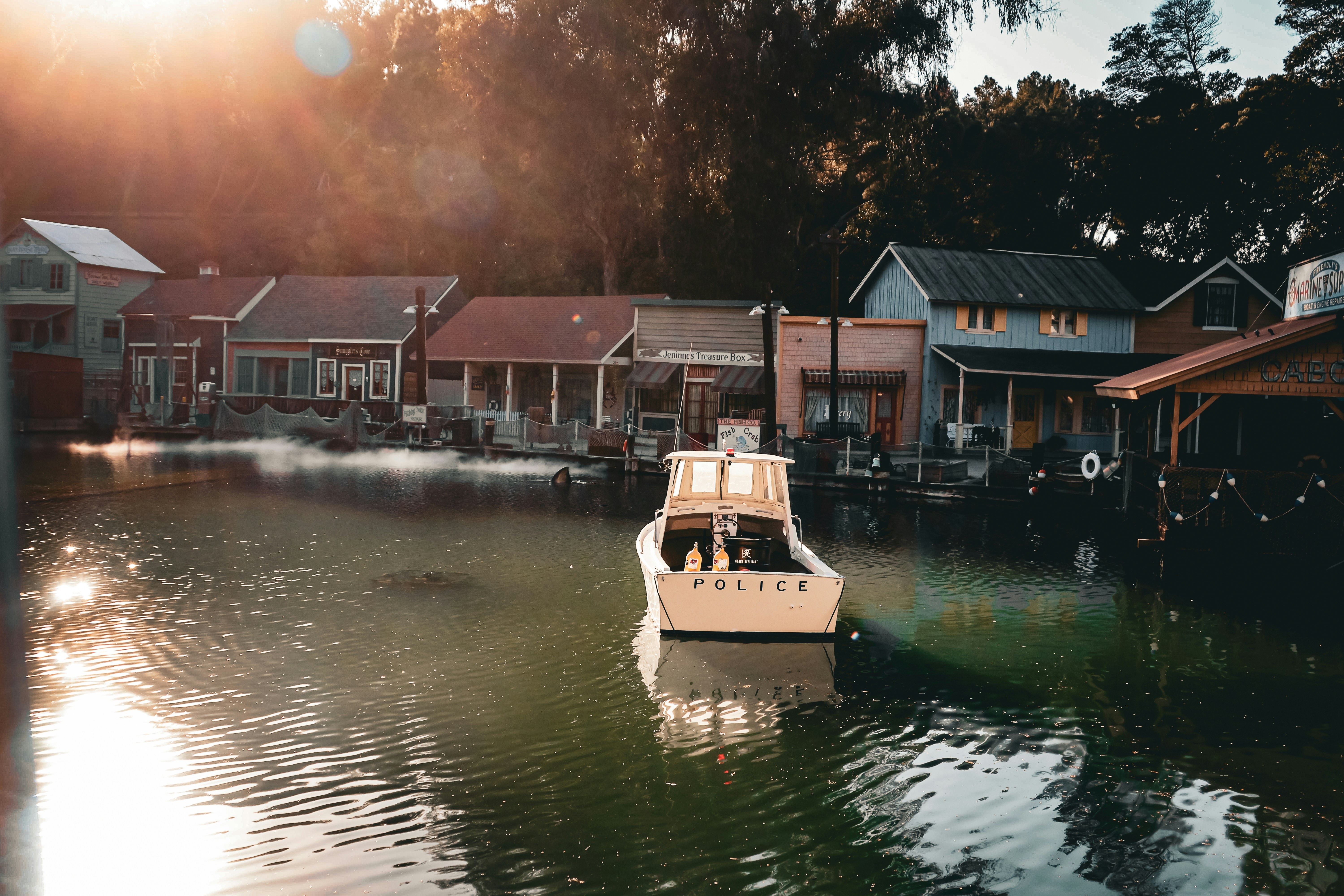 A boat floats by waterfront houses in the sun.